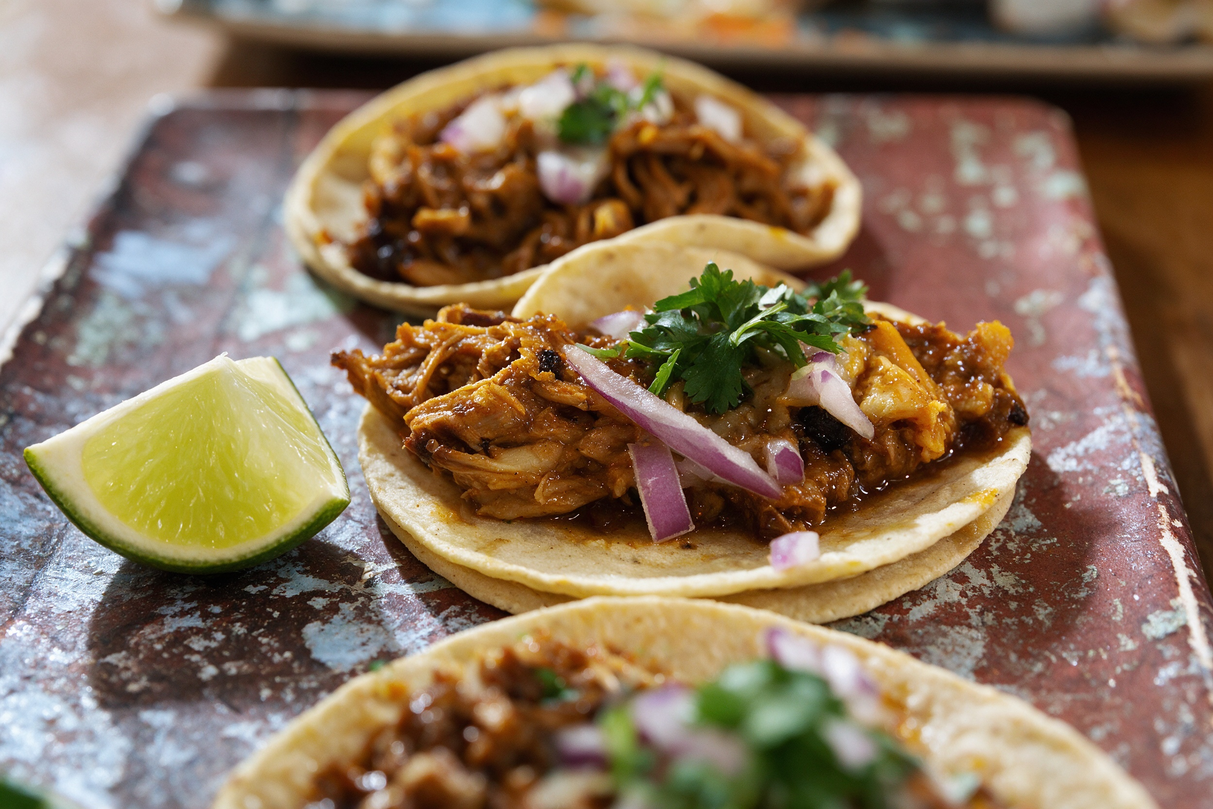 Tacos con carne adobada, cebolla morada y cilantro en tortilla de maíz doble